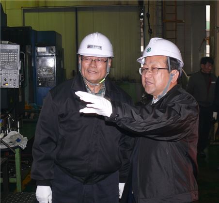 김종준 은행장(오른쪽) 30일 방문 기업중 한 곳인 중앙카프링의 한백술 대표에게서 공장과 제품에 대해 설명을 듣고 있다 ⓒ하나은행