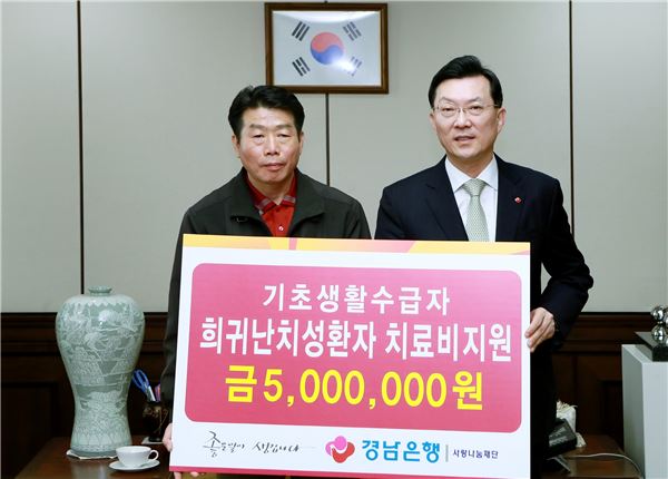 19일 박영빈 경남은행장(오른쪽)이 경남 창원시 마산회원구 본점을 찾은 기초생활수급자 박윤식(58) 씨에게 '치료비 지원증서'를 전달하고 있다. (사진=경남은행)