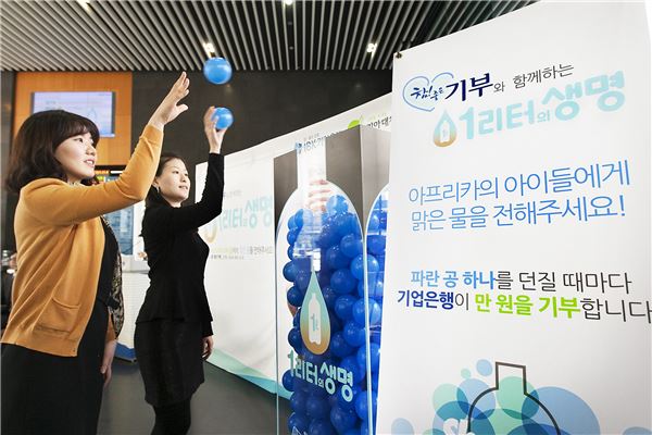29일 서울 중구 을지로 IBK기업은행 본점에서 열린 '아프리카 우물 지원 행사'를 찾은 사람들이 파란색 공을 커다란 생수통에 던져 넣고 있다.