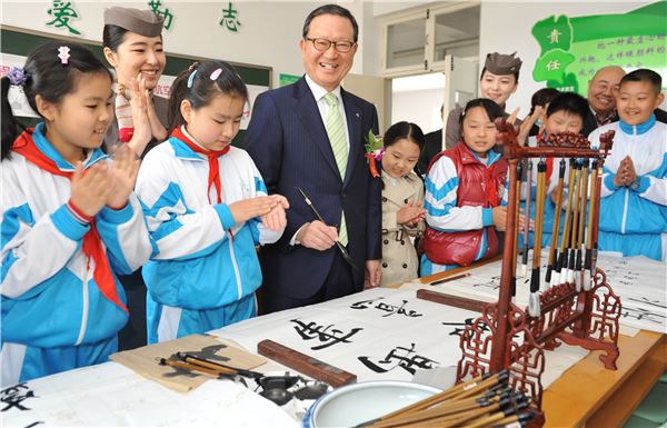 윤영두 아시아나항공 사장이 지난 4월 17일 중국 칭다오 시앙강루소학교에서 열린 글로벌 사회공헌 캠페인 '아름다운 교실' 행사에서 학생들과 서예를 하고 있다. 사진 제공=아시아나항공