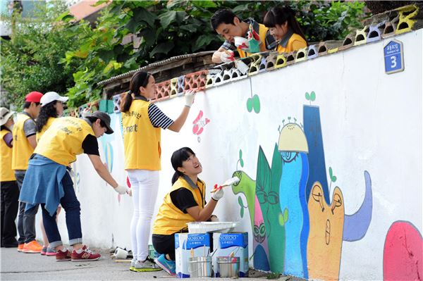 21일 오전 강원도 속초시 교동 소외된 지역 담벼락에 이마트 자원봉사자들이 벽화를 그리며 함박웃음을 짓고 있다. 사진=이마트 제공