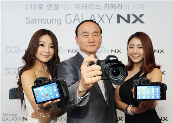 서초동 삼성전자 딜라이트에서 삼성전자 디지털이미징사업부장 한명섭 전무(가운데)와 모델들이 신제품 '갤럭시 NX'를 선보이는 모습. 사진=삼성전자 제공<br />
