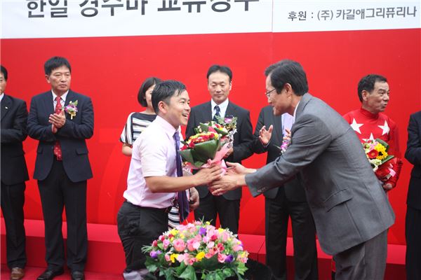 우승 꽃다발을 받고 있는 토센아처의 하시모토 감독