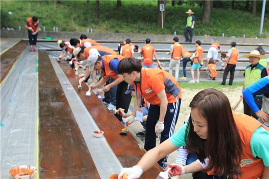 지난달 31일 서울 성동구 서울숲에서 ‘호반사랑나눔이’ 봉사단원들이 시설물에 페인트칠을 하고 있다. 사진=호반건설 제공