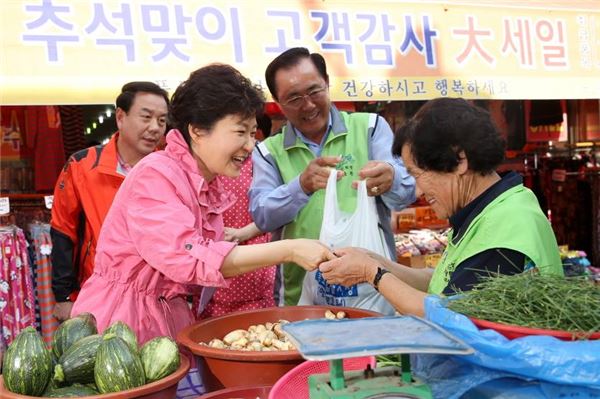 박근혜 대통령이 지난 추석 연휴를 맞아 재래시장을 찾아 물건을 구매하고 있다.  사진=청와대 제공