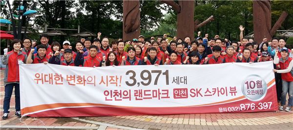 SK건설 자원봉사단이 분양 홍보 현수막을 들고 기념 촬영을 하고 있다. 사진=SK건설 제공