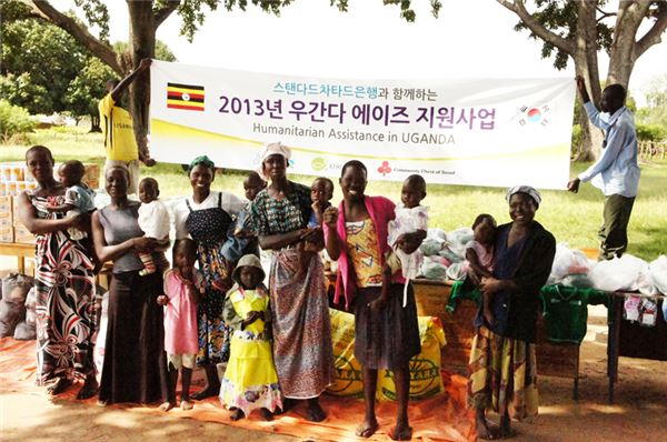 아프리카 우간다 에이즈 아동과 산모들이 에이즈 예방키트와 위생키트를 받고 기념 촬영을 하고 있다. 사진=한국스탠다드차타드은행 제공