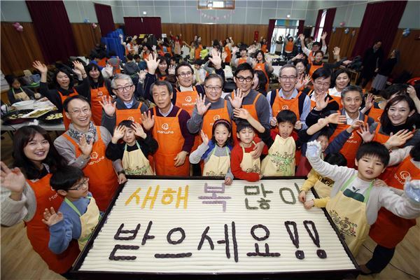한화그룹 CEO와 육아여성직원(워킹맘) 40여명은 22일 서울 은평구에 있는 서울특별시 꿈나무마을을 찾아 설맞이 봉사활동을 진행했다. CEO와 봉사단원, 꿈나무마을 아동들이 손수 새해 인사말을 새긴 가래떡을 배경으로 기념촬영을 하고 있다. (사진 = 한화그룹)