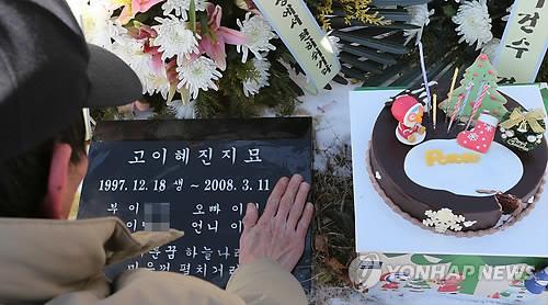 2012년 12월 24일 경기도 안양시립청계공원묘지에서 진행된 '안양 초등학생 혜진·예슬 양 5주기' 추모식에서 혜진 양의 아버지가 묘소 앞에서 딸의 이름을 쓰다듬고 있다. (사진=연합뉴스)