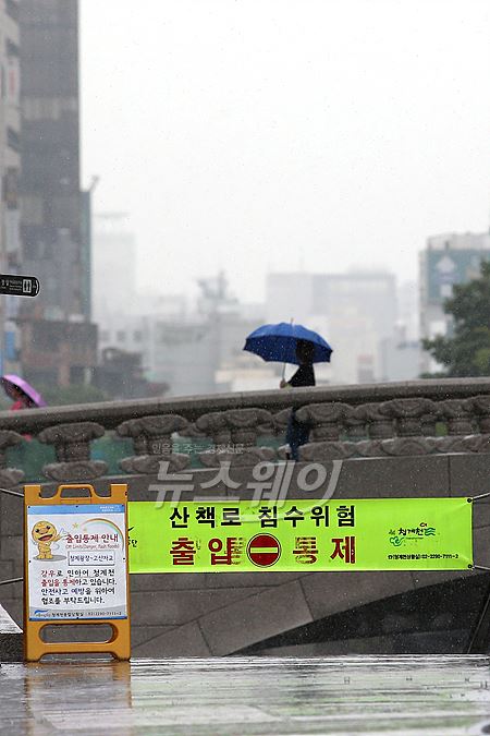 24일 오전 산책로 침수위험으로 통제된 청계천 시작지점 모전교 위를 시민이 우산을 쓰고 걷고 있다. 사진=이수길 기자 leo2004@newsway.co.kr
