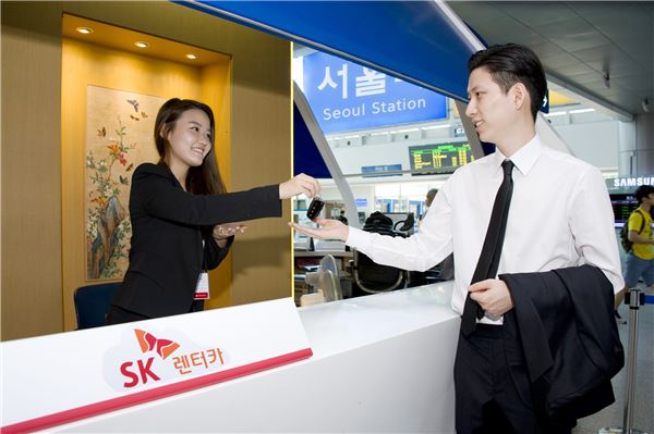 SK렌터카는 서울역 종합안내소에 지점을 개설하고 서비스에 나섰다. 2일 오전 KTX를 타고 서울역에 올라온 고객이 렌터카 계약서를 작성 후 차량 키를 받고 있다. 사진 = SK네트웍스 제공