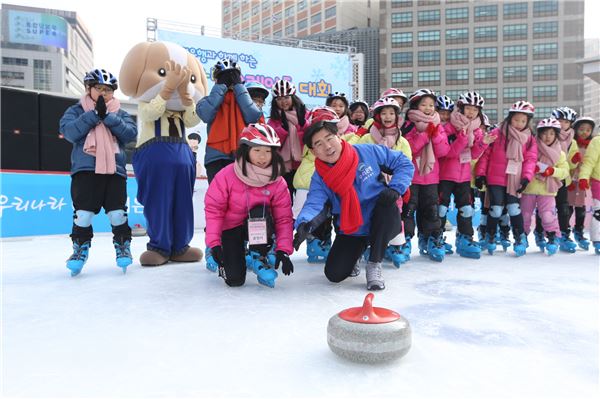 23일 이광구 우리은행장(가운데)이 서울광장 스케이트장에서 열린 ‘우리은행과 함께하는 신나는 스케이트 대회’ 에서 지역아동센터 어린이들과 컬링 체험을 하고 있다.