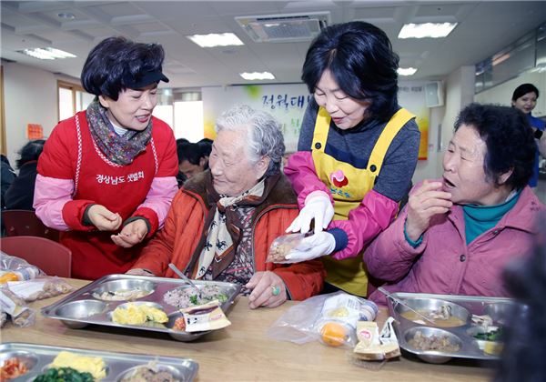 경상남도 홍준표 도지사 부인 이순삼 여사(사진 왼쪽 첫번째)와 경남은행 손교덕 은행장 부인 송혜경 여사(사진 오른쪽 두번째)가 사랑의 특식 나눔 행사장을 찾은 식수자들에게 부럼을 나눠주고 있다. 사진=경남은행 제공