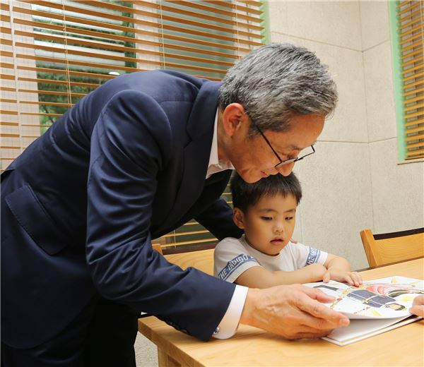 윤종규 KKB국민은행장이 도서관을 찾은 아이에게 책을 읽어주고 있다. 사진=KB국민은행