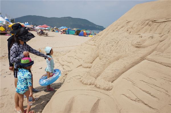 ‘2015 한국 필립모리스 바다사랑 캠페인’의 일환으로 제작된 환경 주제 모래조각 작품을 감상하는 피서객들의 모습