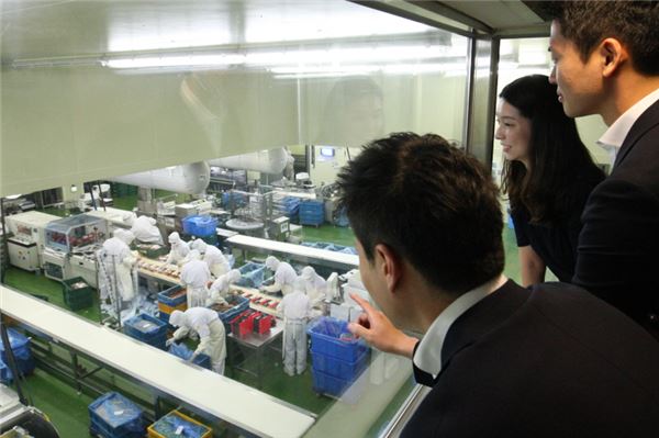 애널리스트가 GS리테일 FRESH FOOD 제조 공장인 후레쉬서브를 방문하여 견학 부스에서 공장 내부를 살펴보고 있다