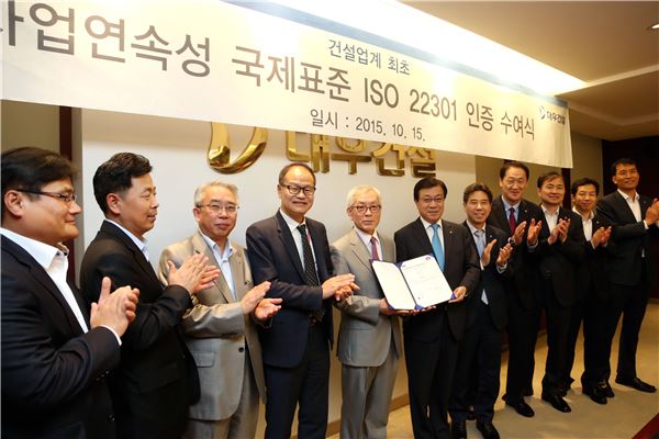 대우건설 지홍근 HSE-Q실장(우측)과 BSI Korea 천정기 회장(좌측)이 ISO 22301 인증패를 들고 관계자들과 함께 기념촬영을 하고 있다.(출처=대우건설)