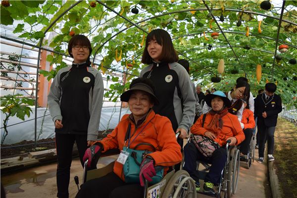 지난 28일 함평 국향대전 축제장에 군의 장애인 재활프로그램에 참여하고 있는 장애인과 가족이 함박웃으며 자원봉사들의 안내로 구경하고 있다.