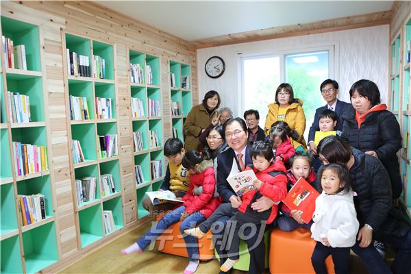 지난 16일 개관한 금당 섬마을 작은 도서관에서 신우철 군수가 책을 읽고 있는 어린이들과 포즈를 취하고 있다.