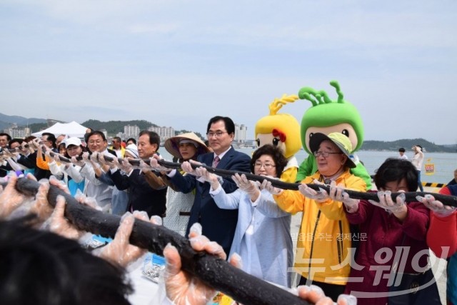 완도장보고수산물축제장에서 신우철 군수를 비롯해 김성훈 전 장관 등 관광객들이 216m의 해조류 김밥을 만들어 함께 들어 올리고 있다.