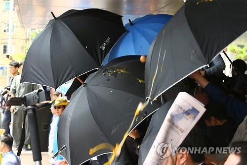 날아오는 계란과 물병을 막기위한 우산들(사진=연합뉴스 제공)