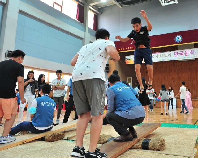 포스코건설 임직원과 인천한누리학교 다문화청소년들이 한국 전통 놀이인 널뛰기를 하고 있다. 사진=포스코건설 제공