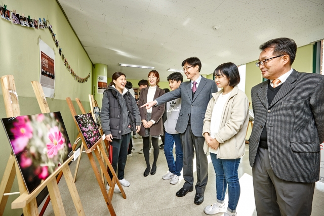 금호타이어와 함께 하는 무빙포토클래스 전시회 작품들을 감상중인 서울 강서구 경서중학교 이상수 교장(사진 오른쪽 세번째) 및 교직원과 학생들 모습. 사진=금호타이어 제공