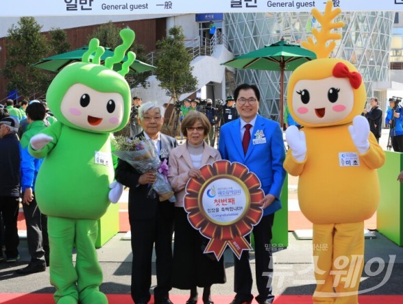 완도국제해조류박람회 외국인 첫 관람객으로 입장한 오오타 요쿠오(78세) 씨가 신우철 조직위원장과 박람회 마스코트인 해토와 미초와 함께 기념사진을 찍고 있다