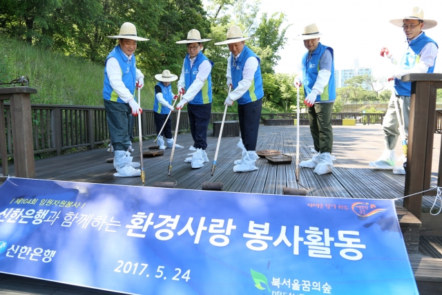 신한은행 임원과 본부장급 직원들이 지난 24일 서울 번동 북서울꿈의숲에서 계단과 공원 내 의자에 부식을 방지하는 오일스텐을 바르는 등의 환경 개선 활동에 참여했다. 사진=신한은행 제공