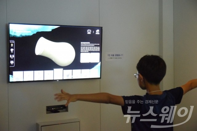 디지털 체험 박물관에서 한 어린이가 지시에 따라 팔을 흔들며 청자를 만들어 보고 있다.
