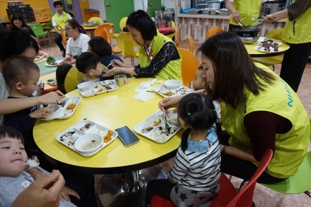 NH농협카드 봉사단이 27일 서울 서대문구에 위치한 구세군 서울후생원에서 아이들의 식사를 돕고 있다.
