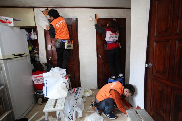 18일 광주광역시 동구 소재 재난위기가정을 찾은 한화손해보험 재난봉사단원들이 도배를 하고 있다.