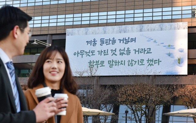 4일 광화문글판 겨울편이 게시된 서울 광화문 교보생명 본사 앞을 지나는 시민들이 대화를 하고 있다.