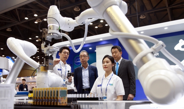박지원 두산중공업 회장이(왼쪽에서 두 번째)이 지난해 9월 열린 ‘2017 로보월드 전시회’에서 두산로보틱스 협동로봇 시연을 지켜보고 있다. 사진=두산 제공