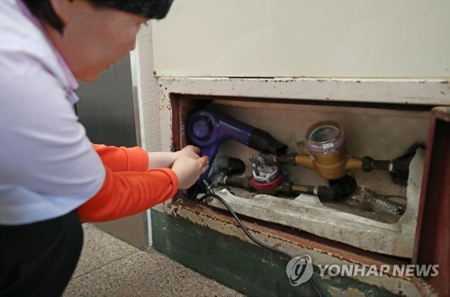 서울 용산구 이촌동의 한 아파트에서 주민이 동파로 교체된 수도 계량기를 헤어드라이어로 녹이고 있다. 사진=연합뉴스 제공