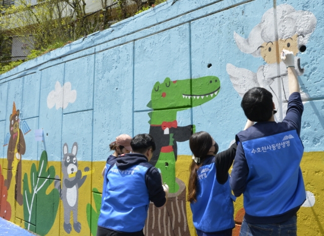 동양생명 직원들이 21일 서울 중랑구에 위치한 상봉초등학교 후문 옆 담장에 벽화를 그리고 있다. 사진=동양생명