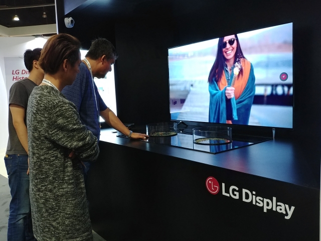 SID 2018에서 LG디스플레이 부스를 방문한 관람객이 화면에서 소리가 나오는 65인치 CSO 제품을 체험하고 있는 모습. 사진=LG디스플레이 제공