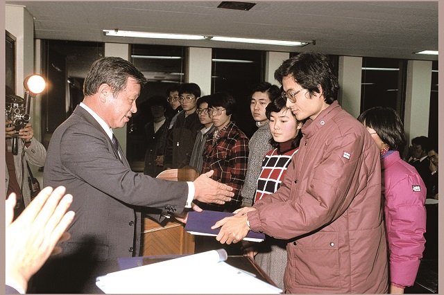 고 최종현 회장(왼쪽)이 1986년 해외 유학을 앞둔 한국고등교육재단 장학생들에게 장학증서를 전달하고 있다. 사진=SK그룹 제공