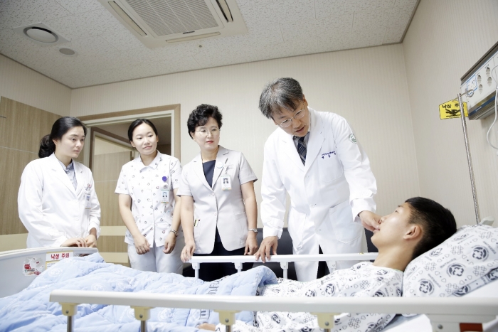 전남대학교치과병원 박홍주 병원장(구강악안면외과 교수·왼쪽에서 네번째)이 성공적인 수술을 마치고 병실에서 회복 중인 오가이유리이 군을 찾아가 위로하고 있다.