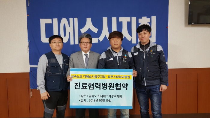 지난 19일 금속노조 디에스시광주지회 임도형 지회장(오른쪽 두번째)과 상무스타치과병원 김재홍 대외협력실장(왼쪽 두번째)이 협약식을 마치고 기념촬영 모습