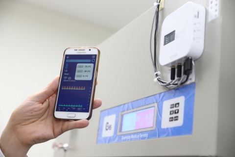 보건소 예방접종실 냉장고에 설치된 IoT온도 센서와 스마트폰 앱에 나타난 온도 데이터.