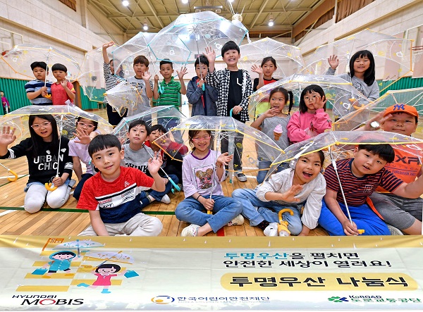 서울 고산초등학교 학생들이 현대모비스가 배포한 투명 우산을 들고포즈를 취하고 있다. 현대모비스는 올해 학교 방문, 개인사연 신청 등을 통해 10만 개 이상의 투명 우산을 배포하며, 2010년부터 배포한 투명 우산은 올해 100만개를 돌파한다. 사진=현대모비스 제공