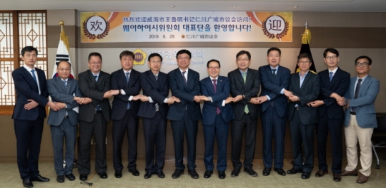 29일 인천시의회 이용범 의장(오른쪽 여섯 번째)이 중국 웨이하이시위원회 대표단과 손을 잡고 기념촬영을 하고 있다.