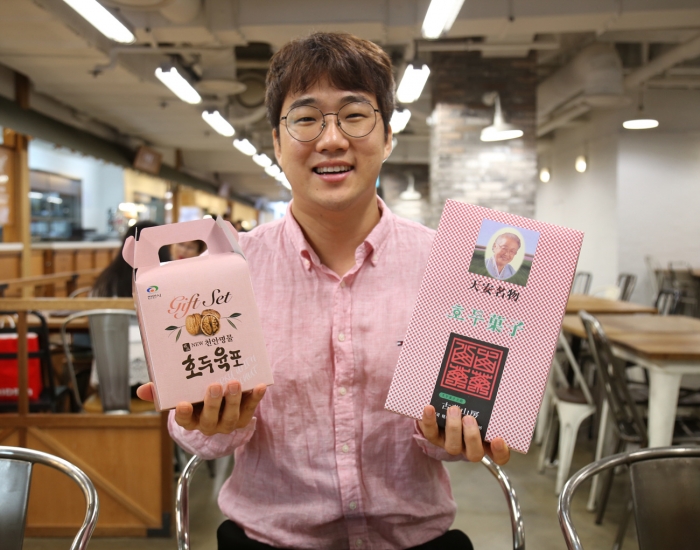 천안명물 특집전을 기획한 야우리 푸드스트리트 박동인MD가 상품을 들고 웃고 있다.(사진=아라리오 제공)