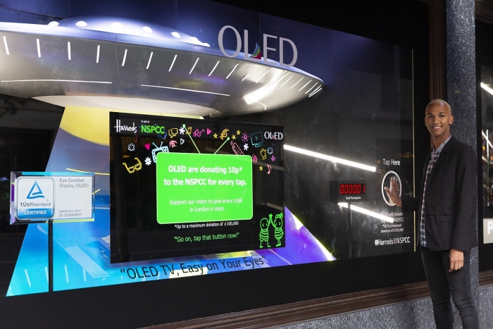LG디스플레이가 영국 해롯백화점 1층 쇼윈도에 설치한 OLED체험형 기부캠페인에 방문객이 손바닥 모양을 클릭해 참여하고 있다. 사진=LG디스플레이