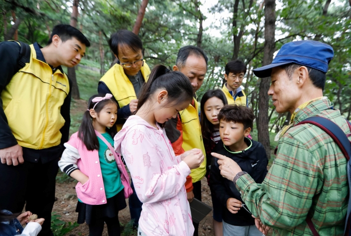 대림산업 임직원 가족들이 숲 해설가와 함께 남산 숲 체험 프로그램에 참여하고 있다. 사진=대림산업 제공