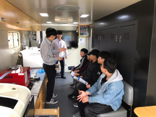 한국석유관리원 직원들이 이동시험실차량 내에서 학생들에게 운영 방법을 설명하고 있다.