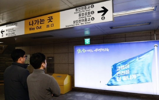 인천시교육청의 교육정책 홍보 포스터를 지나가는 시민들이 바라보고 있다. 사진=인천시교육청