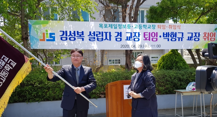 박형규 신임교장이 지난 29일 목포제일정보중·고등학교장 이취임식에서 학교기를 들어 보이고 있다.