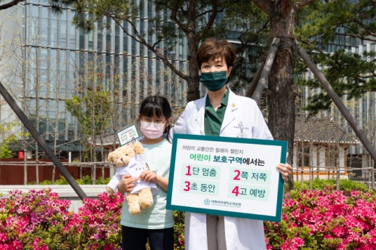 21일 유경하 이화의료원장이 서울 가곡초등학교 3학년 장연규 어린이와 함께 어린이 보호구역 교통안전 릴레이 캠페인에 참여하고 있다.